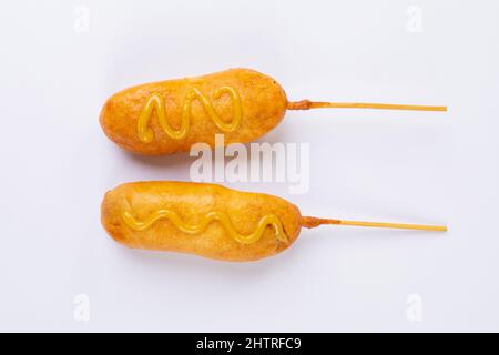 Overhead view of corn dogs over skewers with mustard sauce on white background Stock Photo