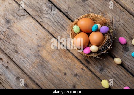 Close-up of easter eggs and colorful candies in nest on wooden table Stock Photo