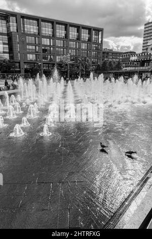 Piccadilly Gardens, Manchester, Greater Manchester, UK, city centre water fountains with pigeons drinking water and buildings in the backdrop. Stock Photo