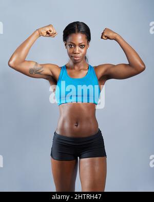 Young African American woman flexing biceps isolated over black