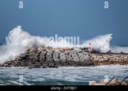 big ocean wave hit in a jetty from a pier in a stormy day Stock Photo