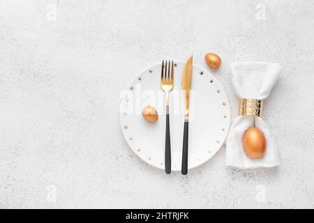Beautiful table setting with golden Easter eggs on white background Stock Photo