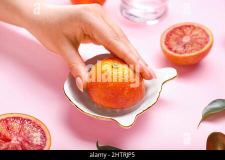 Woman squeezing fresh grapefruit on pink background Stock Photo