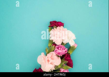 Bunch of flowers in the middle of turquoise background flat lay Stock Photo