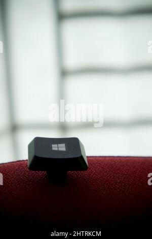 Windows start button of a keyboard in front of a window on a red ...