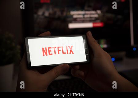 Wroclaw, Poland - JAN 27, 2022: Man with Netflix logo on screen. Netflix is most popular video streaming platform. Stock Photo