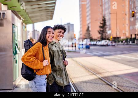 teenage couple waiting at the train or tram stop. young students with a guitar and a ukulele in its case. Stock Photo