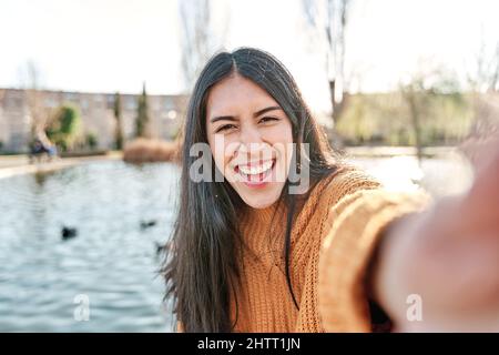 Portrait of charming young woman smiling while taking selfie photo. Stock Photo