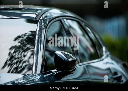 Side view of modern clean shine olive green car parking on a street after the rain, raindrops on the surface of the car. Stock Photo