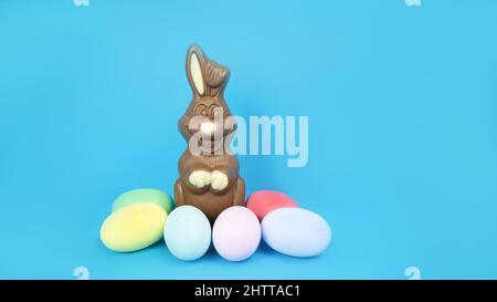 Easter Chocolate Bunny and eggs are plain, multi-colored on a blue background  Stock Photo