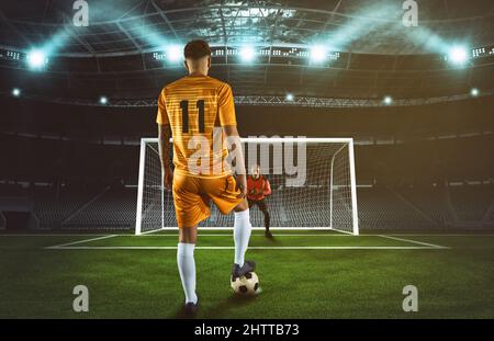 Soccer scene at night match with player in yellow uniform kicking the penalty kick Stock Photo