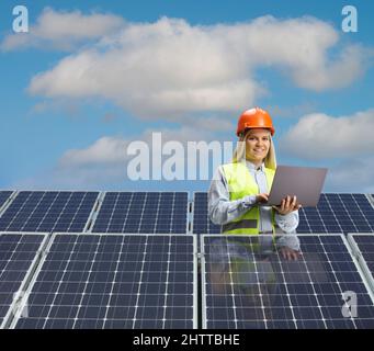 Young female engineer working on a laptop computer behind solar panels Stock Photo
