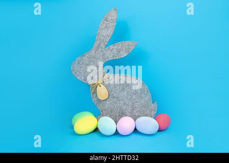 Easter, soft, gray hare and eggs are plain, multi-colored on a blue background.  Stock Photo