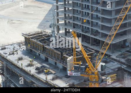 Top view to building construction site with group of builders on roof. Modern skyscraper building construction in UAE Stock Photo