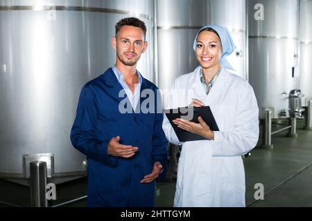 two workers in coats on winery manufactory. Stock Photo
