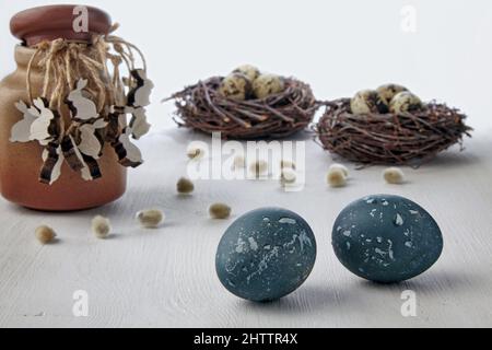 Painted chicken eggs and wooden figurines of hares on the background of bird's nests Stock Photo