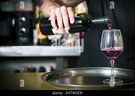 Closeup of a Waiter putting wine in a glass inside the bar Stock Photo