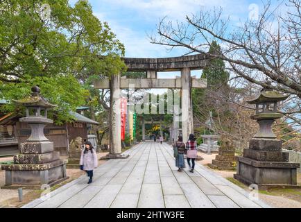 kyushu, japan - december 08 2021: Japanese tourists strolling along the sacred sandō path of Miyajidake Shrine surrounded by stone lanterns and komain Stock Photo