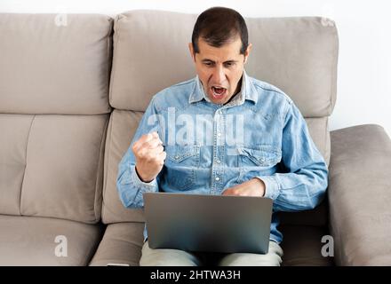 A businessman looking frustrated while working on his laptop at home Stock Photo