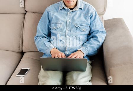 Cropped shot of an unrecognizable man using a laptop in his living room at home office Stock Photo