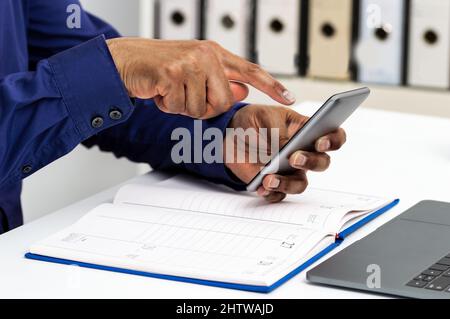 Closeup shot of an unrecognizable executive man hands with agenda using phone at office Stock Photo