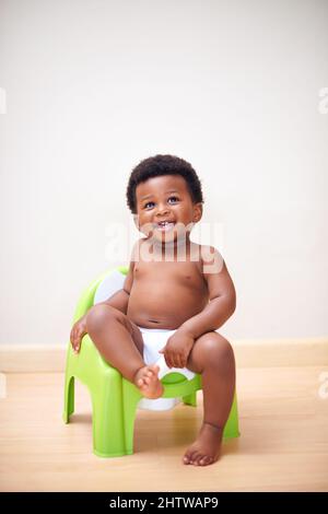 Ive got this potty training thing down. Shot of an adorable baby boy sitting on a potty training seat. Stock Photo