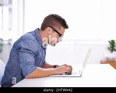 Modern business Fast-paced, innovative and online. A young creative businessman using his laptop. Stock Photo