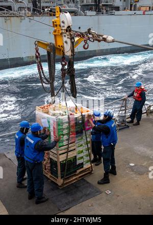 220226-N-HG846-1070 ADRIATIC SEA (Feb. 26, 2022) Sailors aboard Arleigh Burke-class guided-missile destroyer USS Mitscher (DDG 57) receive stores during a replenishment-at-sea with the Supply-class fast combat support ship USNS Supply (T-AOE-6), Feb. 26, 2022. Mitscher is deployed with the Harry S. Truman Carrier Strike Group on a scheduled deployment in the U.S. Sixth Fleet area of operations in support of U.S., allied and partner interests in Europe and Africa. (U.S. Navy photo by Mass Communication Specialist 2nd Class Daniel Serianni) Stock Photo