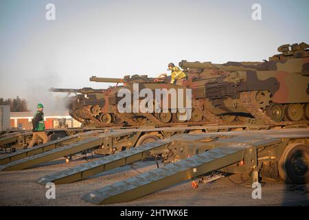 51st Composite Truck Company, 18th CSSB, 16th Sustainment Brigade transports multiple M1 Abrams tanks in Grafenwoehr, Germany, on Feb. 28, 2022.  U.S. Army Europe and Africa is drawing Army Prepositioned Stocks-2 in preparation to support 1st Armored Brigade Combat Team, 3rd Infantry Division deploying to Germany, as announced by the Department of Defense. A complete set for an Armored Brigade Combat Team is currently in the process of delivery to Grafenwoehr Training Area. (U.S. Army photo by Spc. Elizabeth MacPherson) Stock Photo