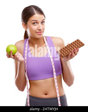 The choice is yours. Shot of a fit young woman holding an apple in one hand and chocolate in the other. Stock Photo