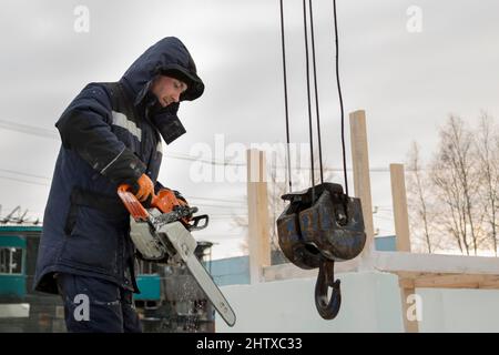 Worker with a chainsaw in hand at the assembly site Stock Photo