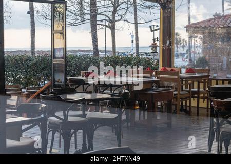 Side, Turkey – February 13 2022:  Restaurant with wooden furniture, lanterns, palm trees on the seaside Stock Photo