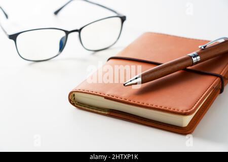 Leather notebook, pen and glasses placed on a white background. Business image. Stock Photo
