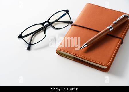 Leather notebook, pen and glasses placed on a white background. Business image. Stock Photo