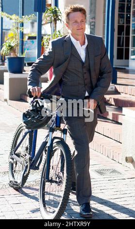 Making the conscientious commuter choice. Shot of an attractive young man pushing his bicycle on the way to work. Stock Photo