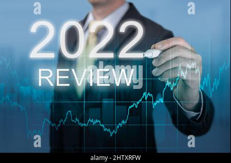 businessman writes 2022 review words. last year review in business. economic indicators, overcoming crisis and economic recovery after coronavirus pan Stock Photo