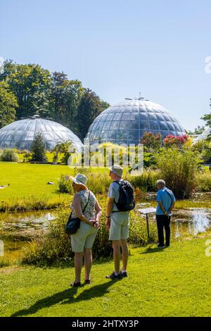 Visitors in the Botanical Garden, domes of the greenhouses at the back, Zurich, Switzerland Stock Photo