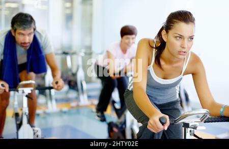 Woman practicing on speed bike at gym. Beautiful woman working out on a stationary bike at the gym. Stock Photo
