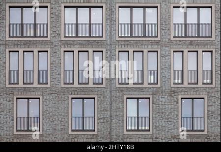 Background image - brick wall of a building with windows of different sizes. Stock Photo