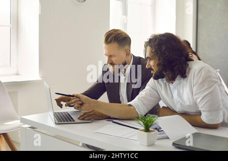 Two business people working on laptop, doing research and discussing marketing strategy Stock Photo