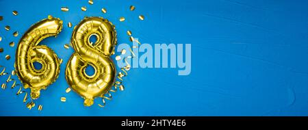 number sixty eight golden yellow foil balloon on blue concrete background. Birthday or anniversary card with the inscription 68. Anniversary celebrati Stock Photo