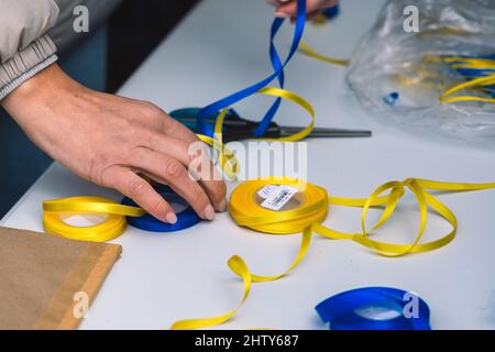 Girl preparing ribbons with colors of Ukraine during a peaceful demonstration against war, Putin and Russia Stock Photo
