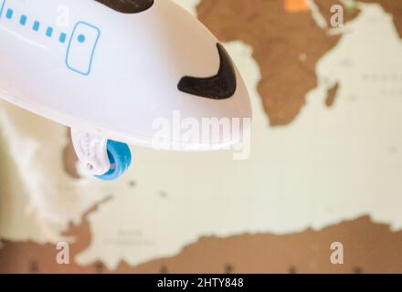 The concept of travel and flight, a miniature of a white airplane in close-up on the background of a world map. Stock Photo