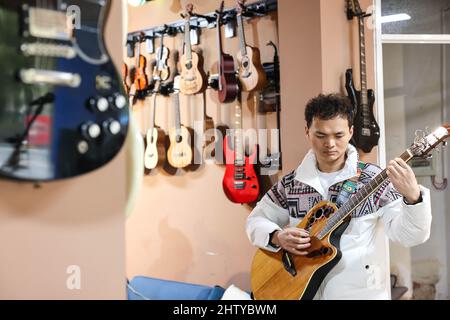 (220303) -- GUIYANG, March 3, 2022 (Xinhua) -- Guitarist Yang Zhi practices in Guiyang, southwest China's Guizhou Province, March 1, 2022. A band named 'Fish Mint' consists of three massage therapists and a delivery man who were all born in the 1990s. Yet the delivery man is the only one who could see while the rest are with visual impairment. The members do their regular work during the day and gather around to play music in the band in the evening. The band is named after fish mint, as the members think they bear a resemblance to it. Fish mint, the leaf vegetable favored by the local p Stock Photo