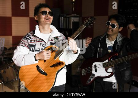 (220303) -- GUIYANG, March 3, 2022 (Xinhua) -- Guitarist Yang Zhi (L) and bassist Peng Wanhai practice in Guiyang, southwest China's Guizhou Province, March 1, 2022. A band named 'Fish Mint' consists of three massage therapists and a delivery man who were all born in the 1990s. Yet the delivery man is the only one who could see while the rest are with visual impairment. The members do their regular work during the day and gather around to play music in the band in the evening. The band is named after fish mint, as the members think they bear a resemblance to it. Fish mint, the leaf veget Stock Photo