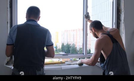 Dismantling and installation of a window in an apartment by two workers: Moscow, Russia - August 17, 2021. Stock Photo