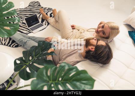content caucasian couple celebrating Valentine's Day laying on the floor, looking at each other, and smiling. High quality photo Stock Photo