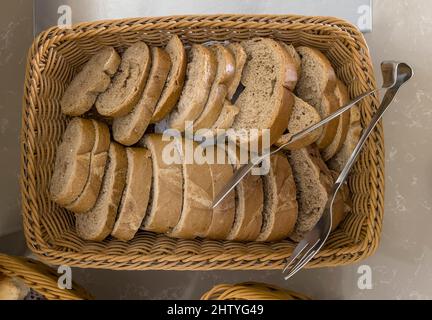 Delicious slices of black bread on the table in a wicker basket. Top view, close-up. Stock Photo
