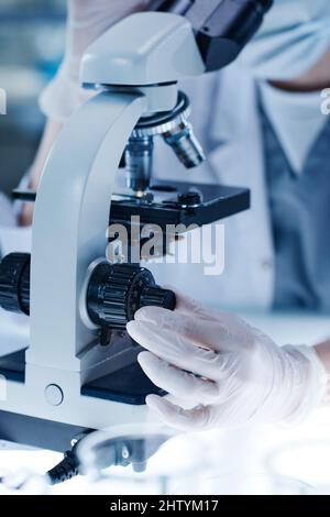 Close-up of scientist adjusting the lenses of a microscope during medical exam in laboratory Stock Photo