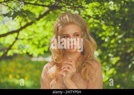 Beautiful fashion model woman enjoying nature, breathing fresh air in summer park over green leaves background Stock Photo